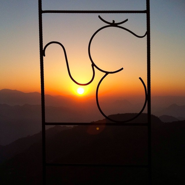 Catching the sunrise high in the mountains, through an Om sign in the fence, naturally.